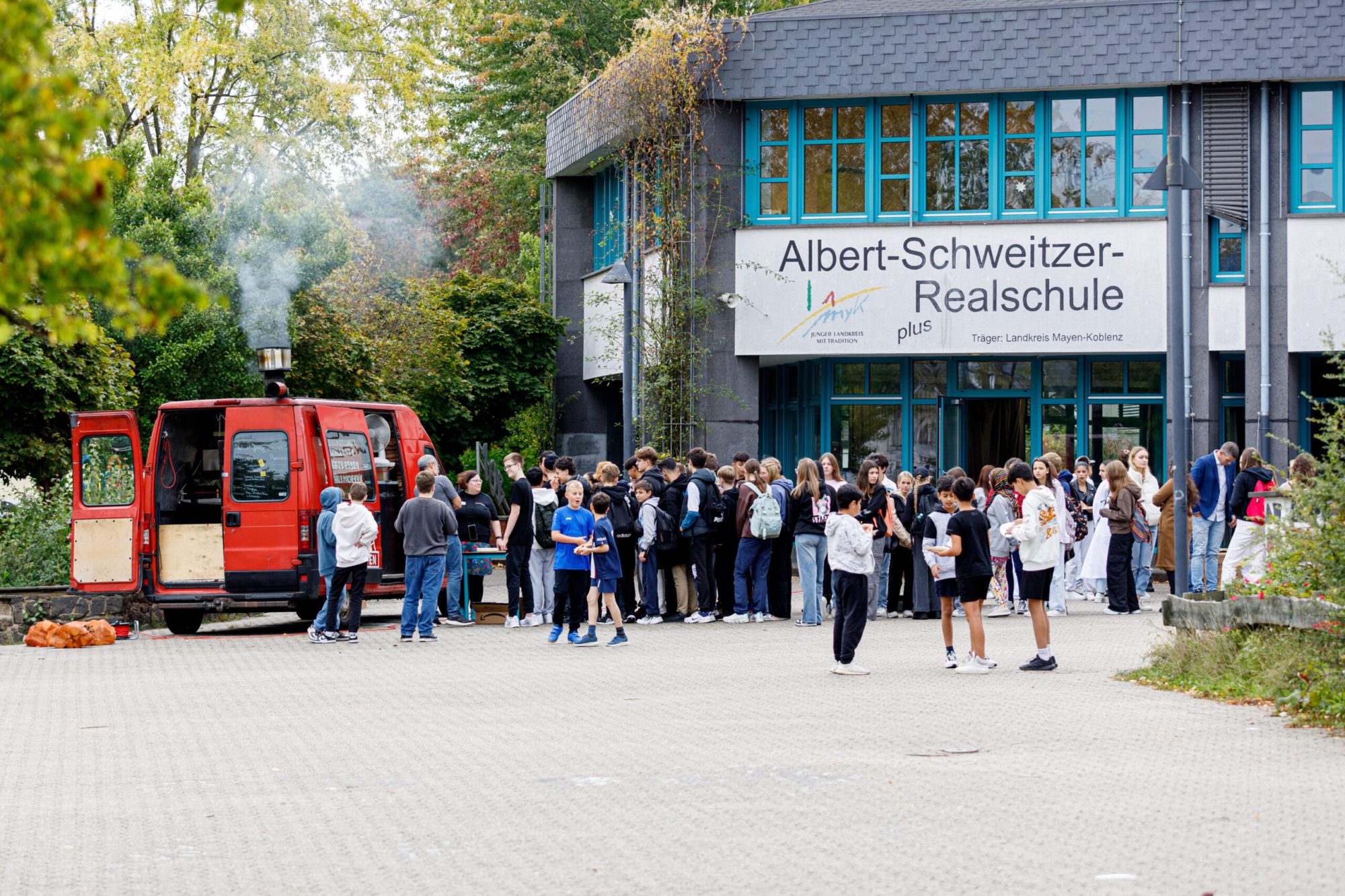 Menschenschlange auf dem Schulhof vor einem Food-Truck.